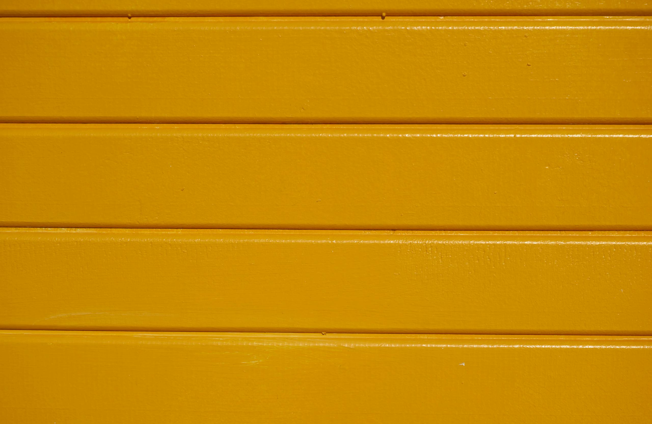 Close-up of yellow painted wooden planks with a clear textured finish.